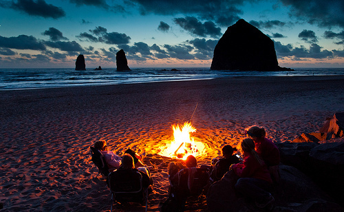 (Cannon Beach, Oregon) A family relaxes in front of Haystack Rock, the largest (72m) sea stack on the US coast. This was the first day of fair weather in weeks on the coast, and the shoeline was dotted with small fires from groups enjoying the sunset.As usual with the people I seem to meet here, they all had relatives in Norway. Or at least these thought they did; as their name started with Mac... I said, sure, you might be Norwegian and took them up on their offer of a shoreside drink or five, to prove my ethnic heritage.I thus missed missed a very nice, partly cloudy post-rain photo op of some large rocks. Oh, well. At last the little girls thought I looked like Johnny Depp. As the Mad Hatter in Alice in Wonderland. I need a haircut.